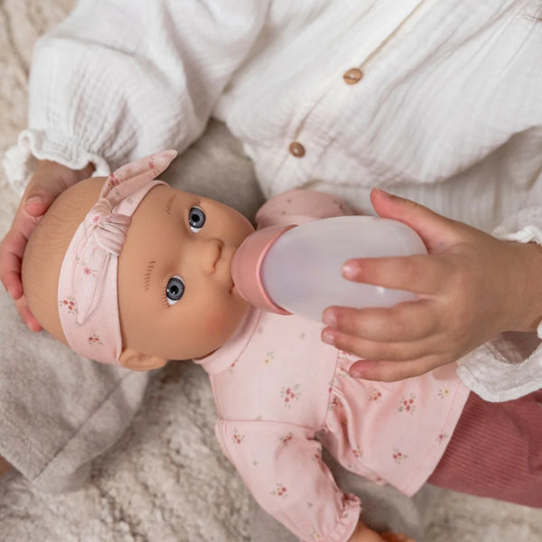 Boneca Lily 36 cm com corpo macio, roupa Rosy Meadows, chupeta e biberão, indicada como primeira boneca para crianças a partir dos 18 meses.