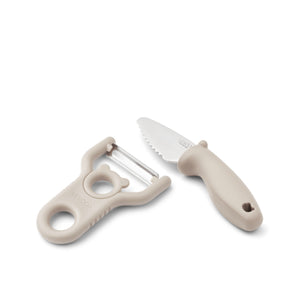 Conjunto infantil de descascador e faca com lâminas em aço inoxidável e pegas adaptadas às crianças para preparação de alimentos.
