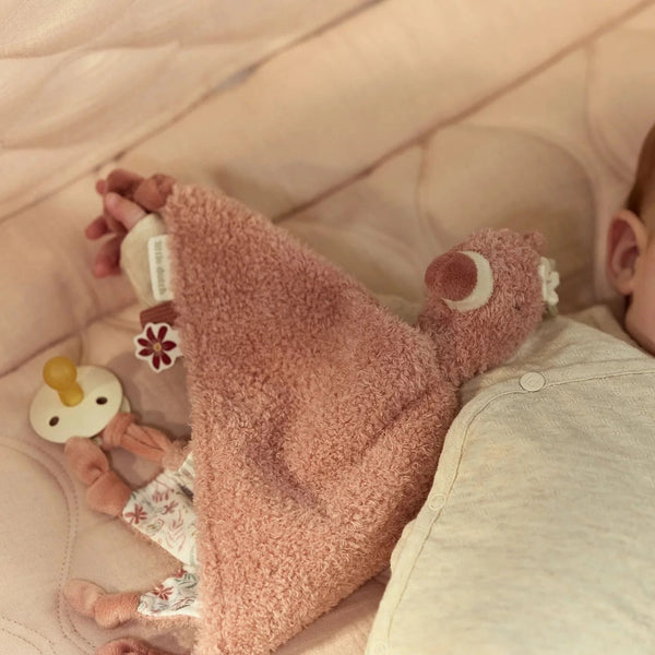 Doudou Flamingo em tecido macio com etiquetas sensoriais e fita para prender chupeta ou mordedor, ideal para confortar e estimular o bebé desde os primeiros meses.