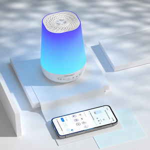 Máquina de Ruído Branco e Luz de Presença Momcozy com 20 sons relaxantes, luz regulável, temporizador e design portátil para ajudar o bebé a dormir melhor.
