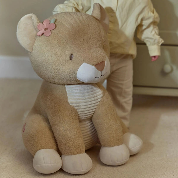 Peluche Leoa Safari Friends de 60 cm em poliéster macio, com detalhe floral junto à orelha, ideal para abraçar e decorar o quarto infantil.
